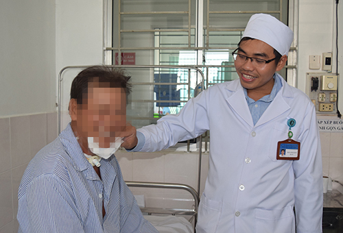 Thạc sĩ - bác sĩ Trần Long Giang, Bệnh viện Tai Mũi Họng TP Cần Thơ thăm hỏi bệnh nhân sau phẫu thuật cắt thanh quản bán phần. Ảnh: K.Nhiên