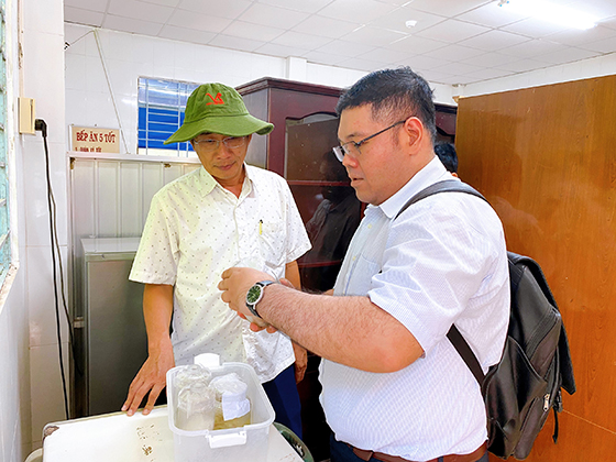 Ông Phạm Phú Trường Giang (bên trái), Phó Giám đốc Sở Y tế kiểm tra lưu mẫu thực phẩm tại bếp ăn tập thể trường Mầm non Tân Xuân.